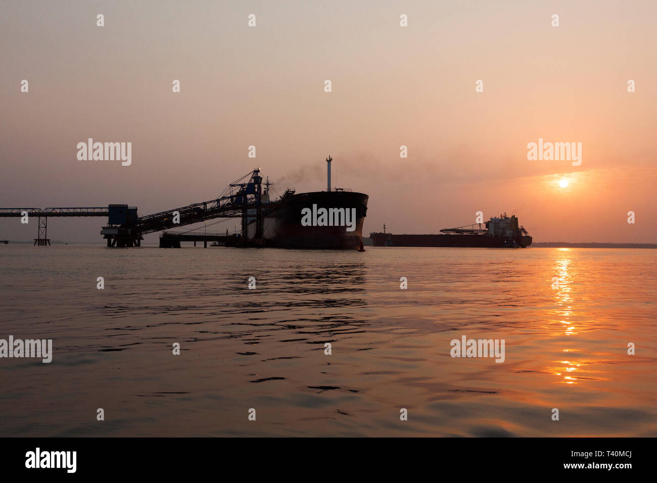 Opérations portuaires pour la gestion et le transport de minerai de fer à l'aube et le lever du soleil avec 2 navires TSV - un quai de chargement à l'un, en attente de dock. La Sierra Leone Banque D'Images