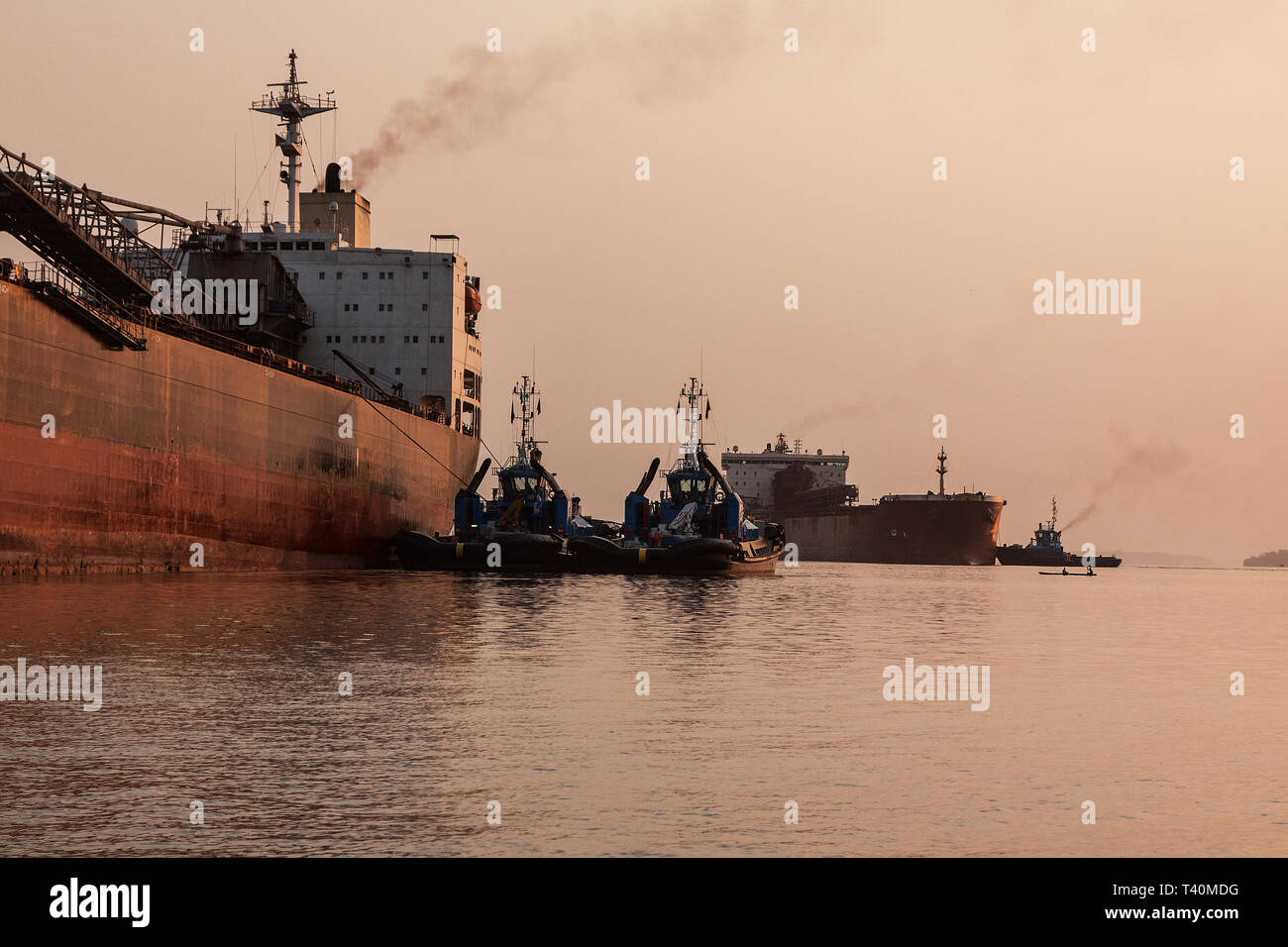 Opérations portuaires pour la gestion et le transport de minerai de fer à l'aube et le lever du soleil avec 2 navires TSV - un quai de chargement à l'un, en attente de dock. La Sierra Leone Banque D'Images