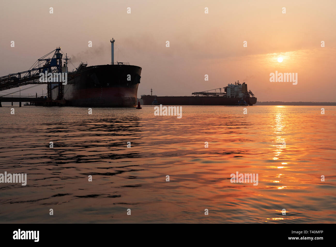 Opérations portuaires pour la gestion et le transport de minerai de fer à l'aube et le lever du soleil avec 2 navires TSV - un quai de chargement à l'un, en attente de dock. La Sierra Leone Banque D'Images