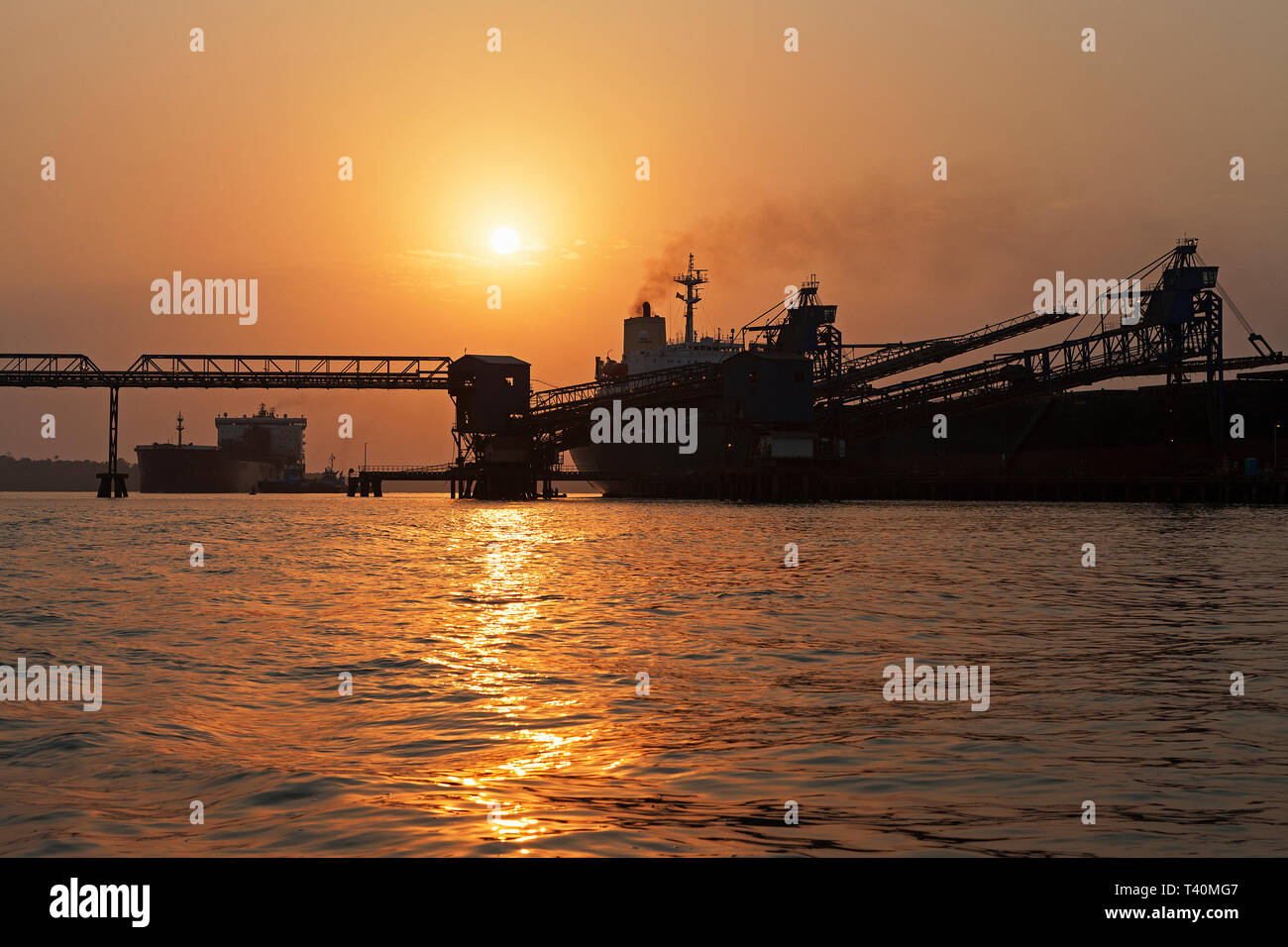 Opérations portuaires pour la gestion et le transport de minerai de fer à l'aube et le lever du soleil avec 2 navires TSV - un quai de chargement à l'un, en attente de dock. La Sierra Leone Banque D'Images