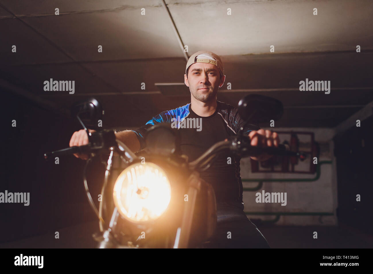 Man fixing bike. Jeune homme confiant la réparation de près de son garage moto. Banque D'Images