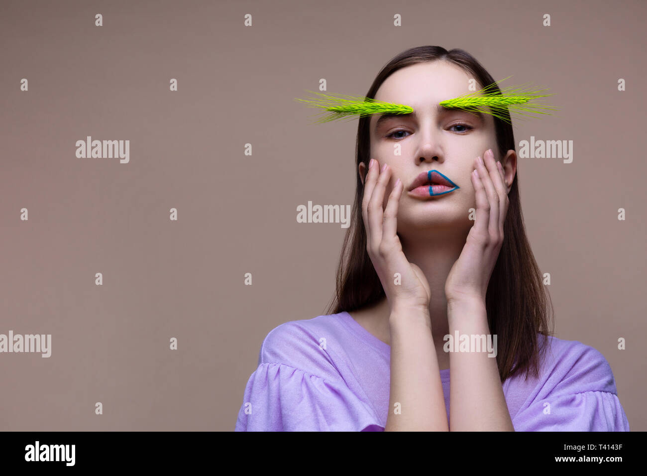 Femme d'épillets vert sur les sourcils touching her face Banque D'Images