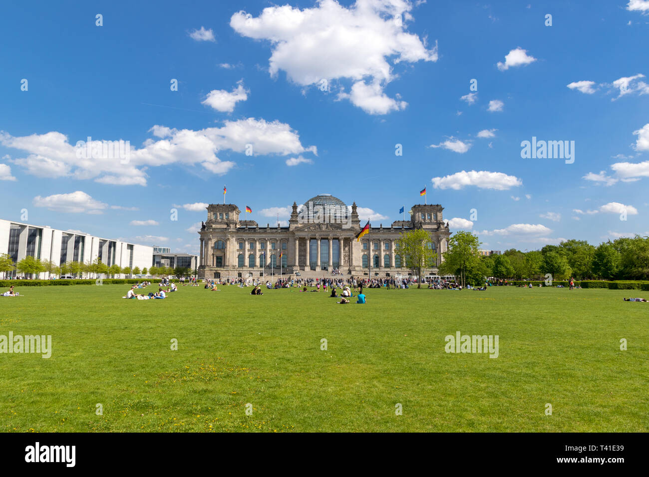 BERLIN, ALLEMAGNE - 28 avril, 2018 : Les gens de vous détendre sur l'herbe, devant le Reichstag, siège du Parlement allemand (Deutscher Bundestag). Banque D'Images