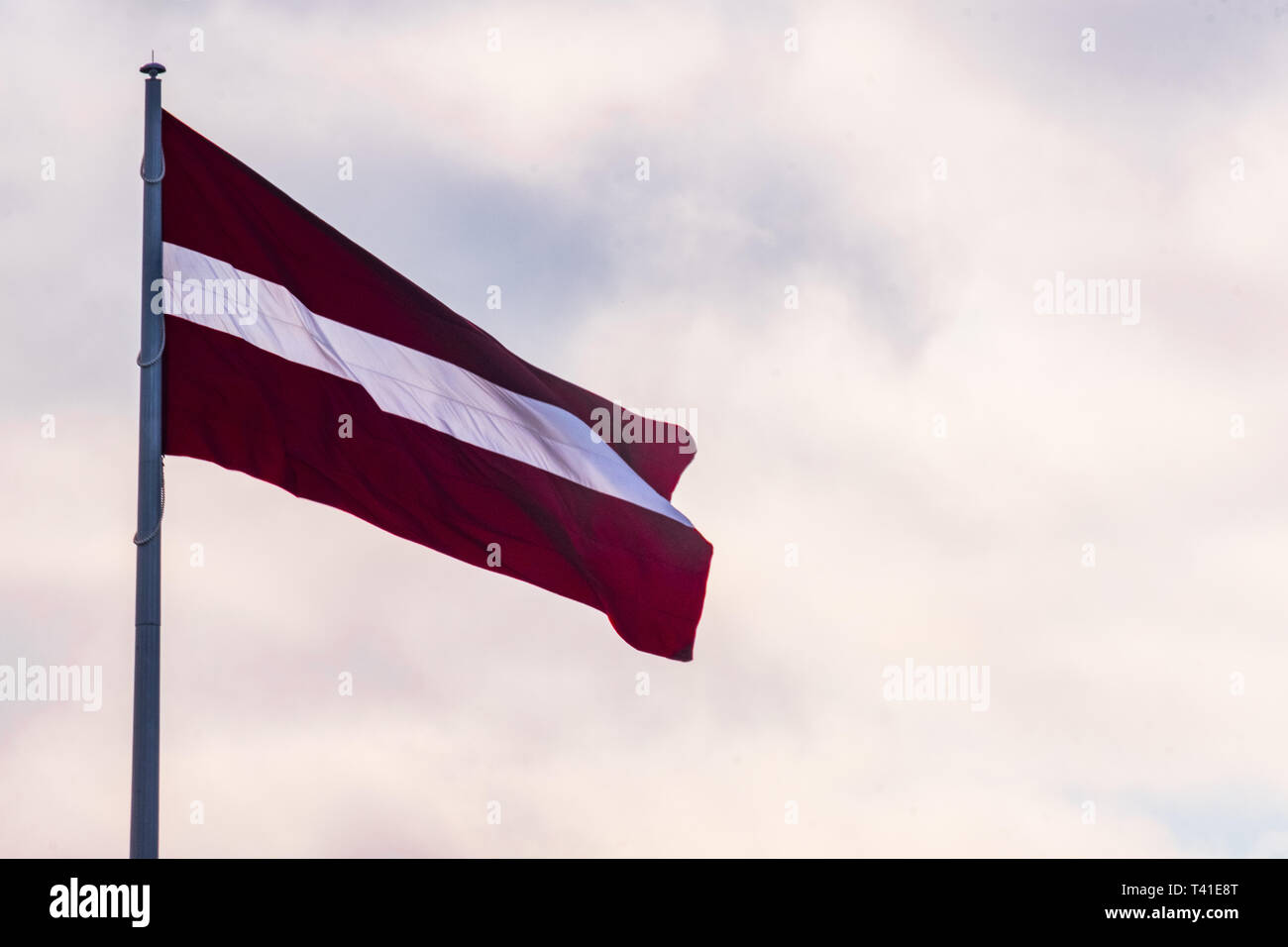 Grand drapeau letton avec des nuages isolés dans l'arrière-plan Banque D'Images