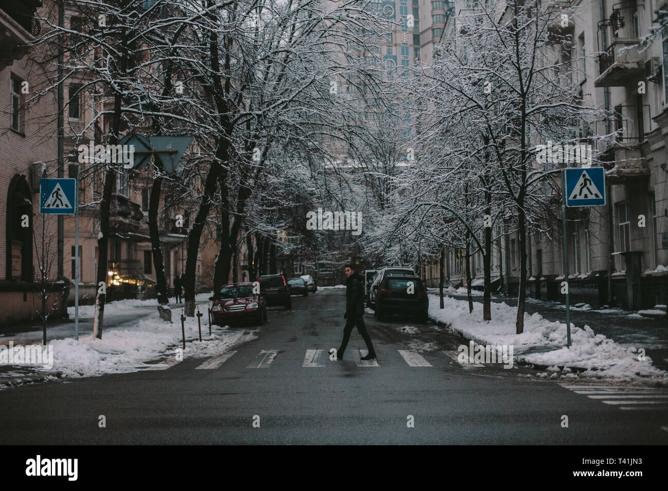 Man crossing city street en hiver Banque D'Images