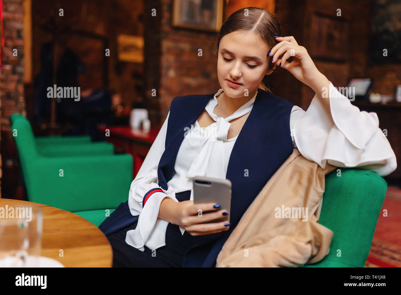 Jeune fille assise confortable avec phone in cafe Banque D'Images