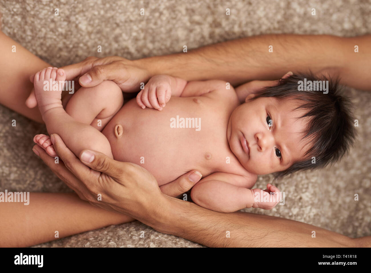 Mignon bébé nouveau-né serra les mains avec les parents vue ci-dessus Banque D'Images
