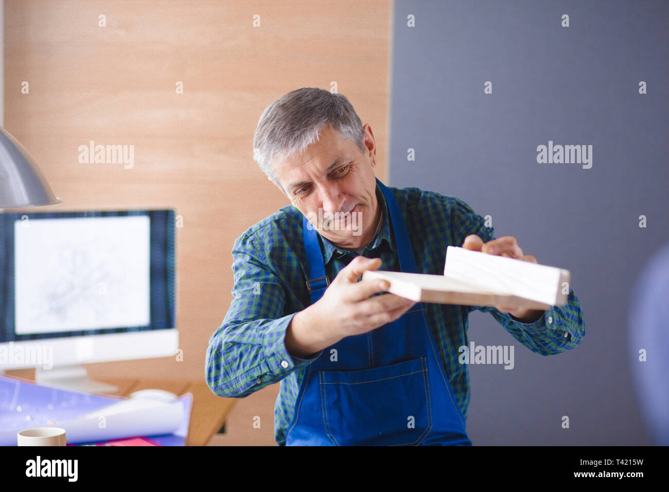 Profession, la menuiserie, la boiserie et les personnes concept - carpenter planche en bois d'essai d'uniformité à l'atelier. Banque D'Images