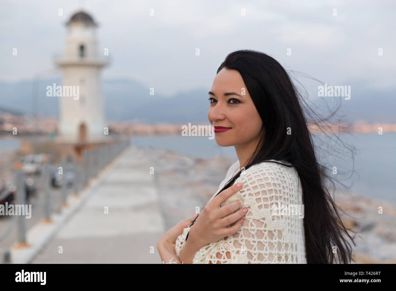 Magnifique Portrait de femme romantique avec macrame foulard sur ses épaules posant devant le phare. Composition horizontale. Copier l'espace. Banque D'Images