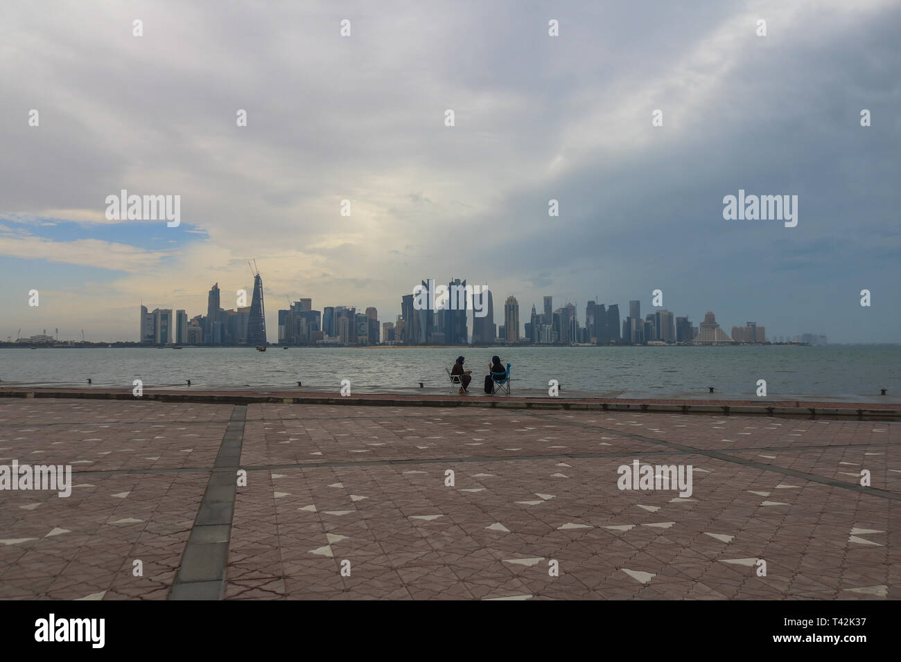 Doha, Qatar. 13 avr, 2019. Deux femmes profiter assis sur le bord de mer avec une vue sur la Corniche de gratte-ciel après une matinée pluvieuse et humide dans le capital Crédit : amer ghazzal/Alamy Live News Banque D'Images