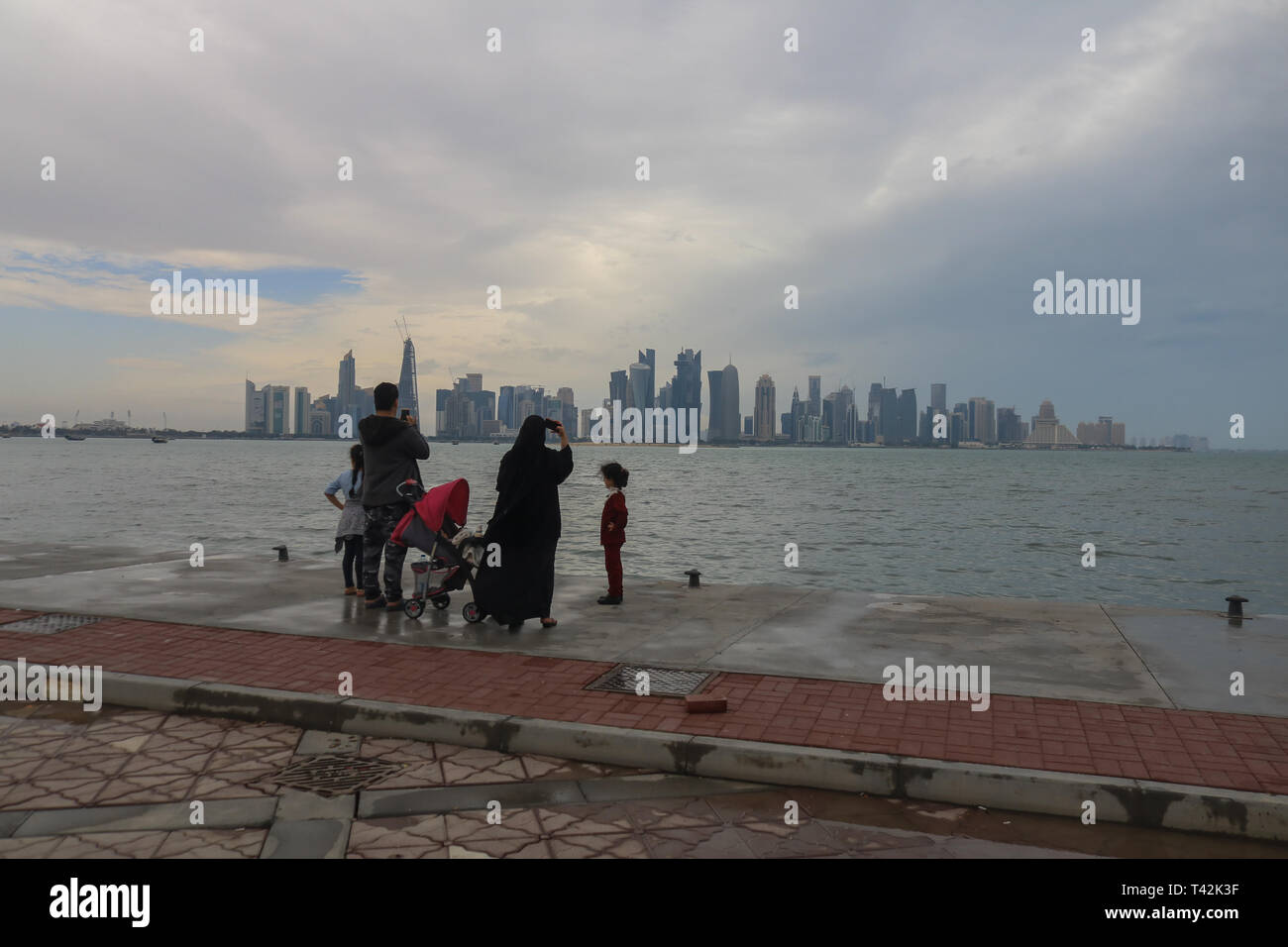 Doha, Qatar. 13 avr, 2019. Une famille d'admirer la vue sur la corniche des gratte-ciel du bord de l'eau sous les nuages de tempête Crédit : amer ghazzal/Alamy Live News Banque D'Images