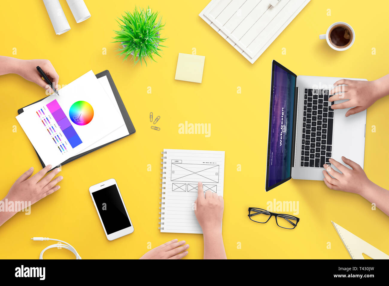 Le travail en équipe sur des projets de conception web. Haut de la vue, télévision jeter scène avec ordinateur portable, smart phone, plans, documents et du café. 24 jaune. Banque D'Images
