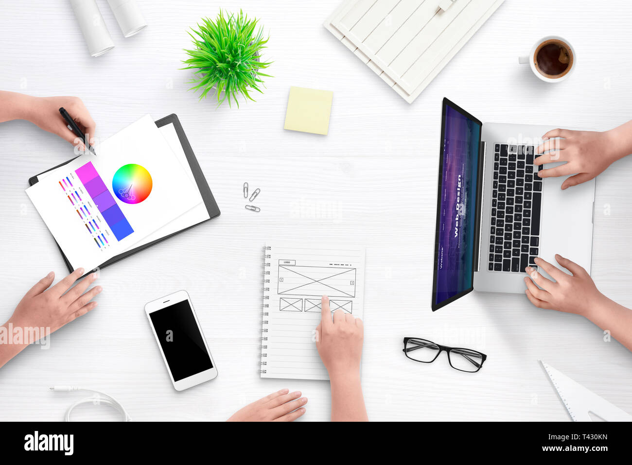 Vue supérieure de la scène de l'équipe de conception web bureau. Ordinateur portable avec télévision site web design concept, idée esquisse sur papier, palette de couleurs, tasse de café, pl Banque D'Images