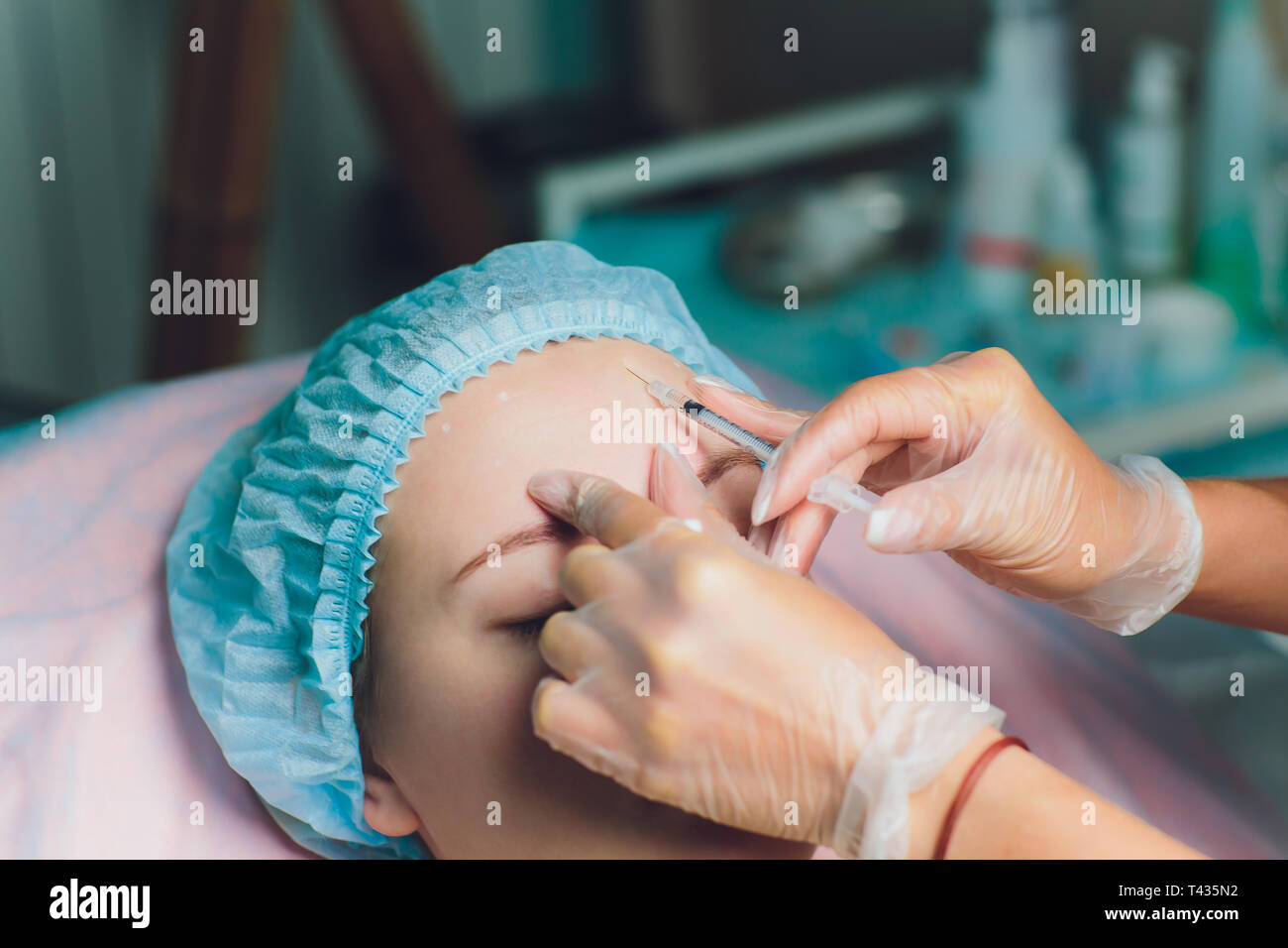 Médecin du visage donnant d'injection sur le milieu de l'âge femme dans le front entre les sourcils pour enlever les rides d'expression clinique dans une salle d'opération O.R Banque D'Images