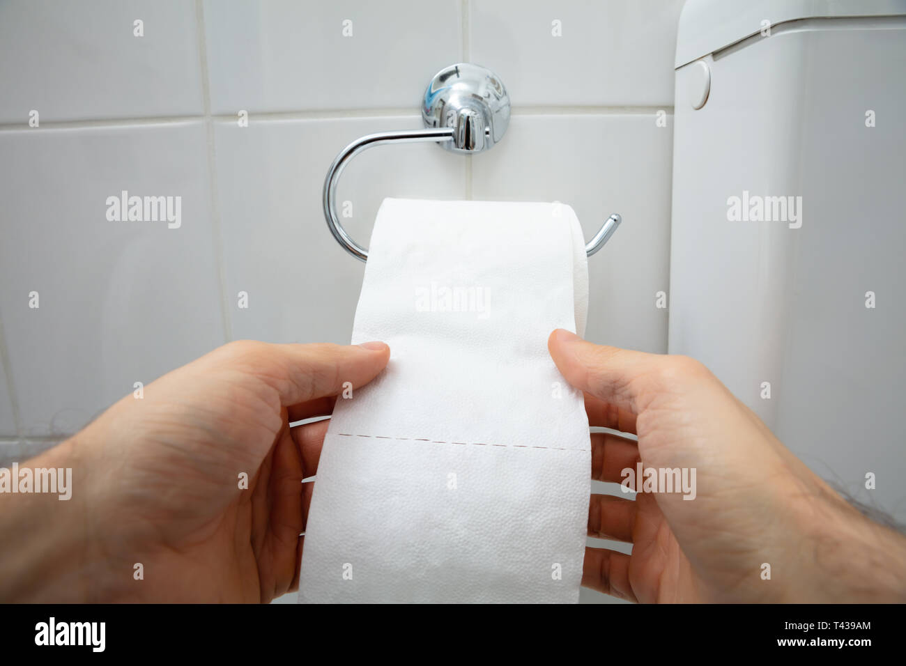 Close-up de la main humaine en utilisant du papier toilette dans la salle de bains Banque D'Images