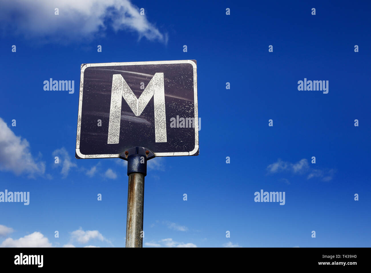 Panneau routier altérés avec la lettre M, pour point de rencontre, contre un fond bleu ciel nuageux. Signe commun sur les routes rurales en Suède Banque D'Images