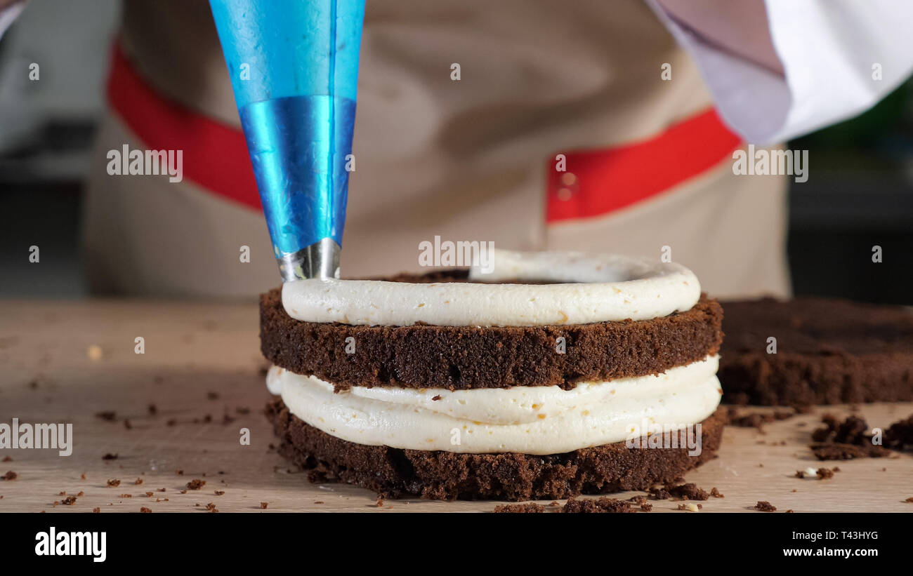 Chef Patissier Verser La Creme Avec Poche A Douille Sur Le Chocolat Gateau Eponge Vue De Cote Les Mains De Pres La Cuisson Et La Production Alimentaire Industrielle Photo Stock Alamy