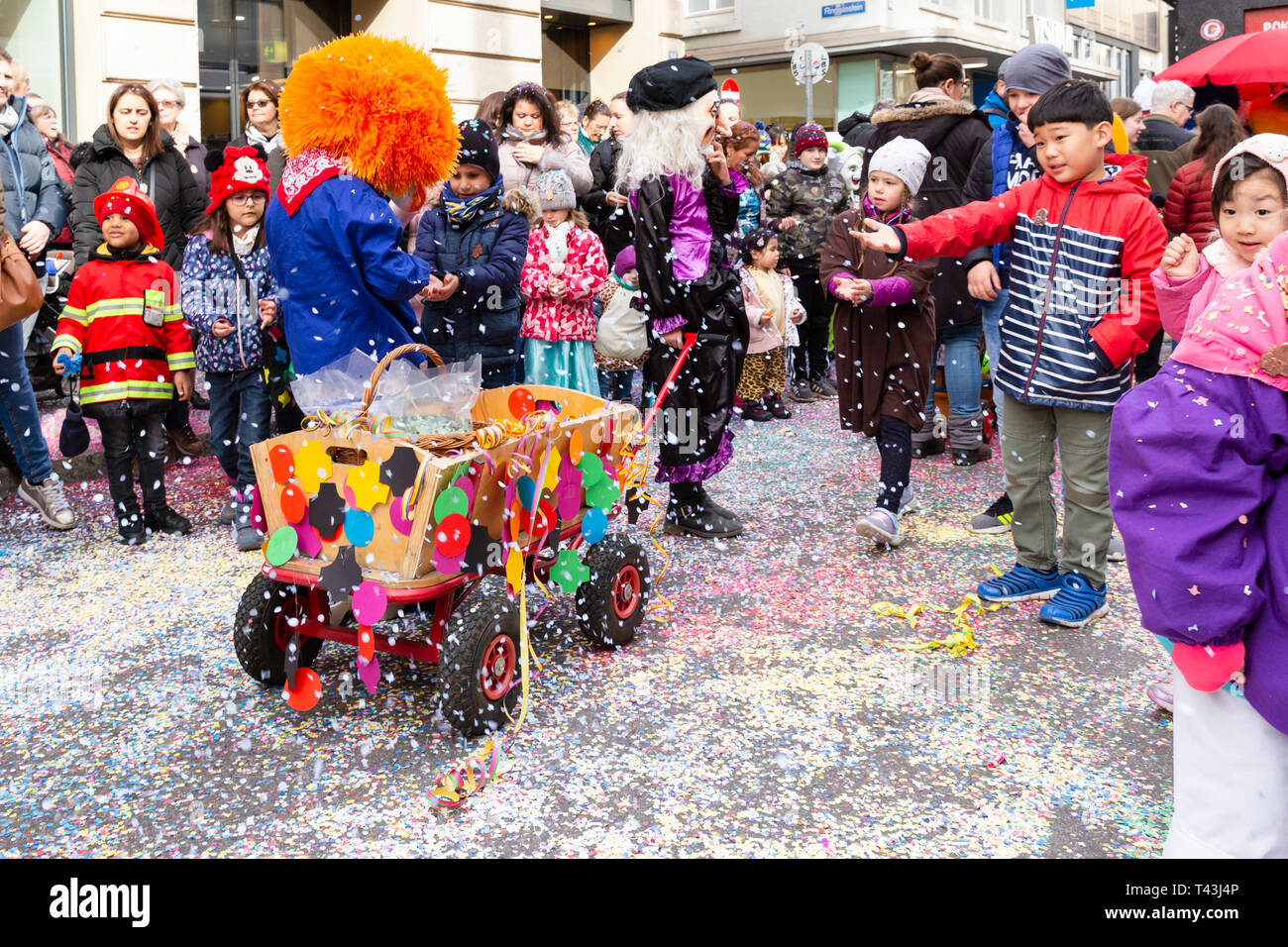 Freie Strasse, Bâle, Suisse - Mars 12th, 2019. Un petit carnaval coloré décoré panier sur une rue couverte de confettis Banque D'Images