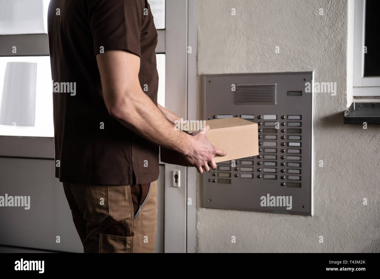 La mi-section de Man Holding Cardboard Box interphone sonnerie Banque D'Images