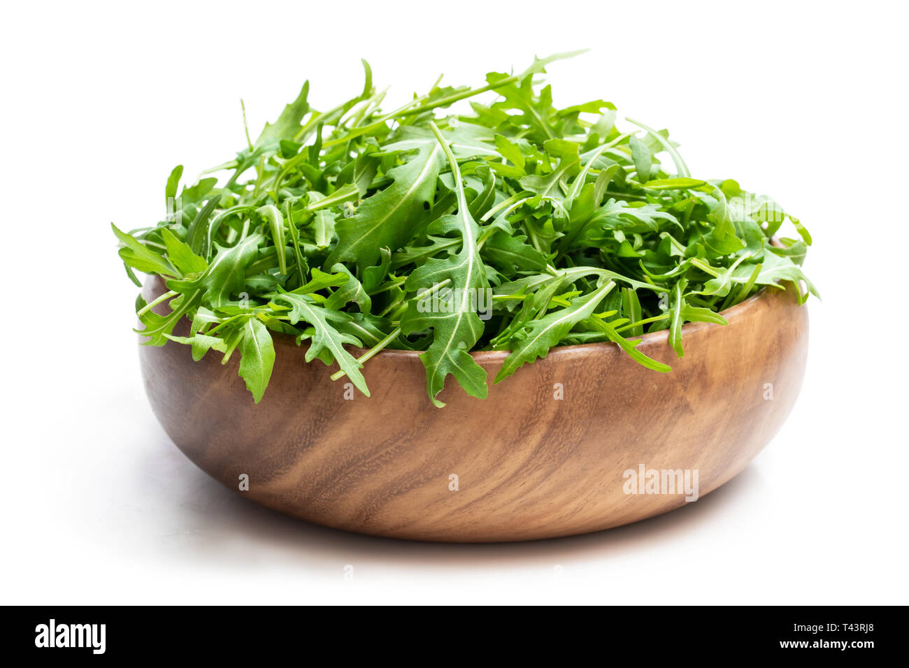 Salade de roquette feuilles dans bol en bois isolé sur blanc Banque D'Images