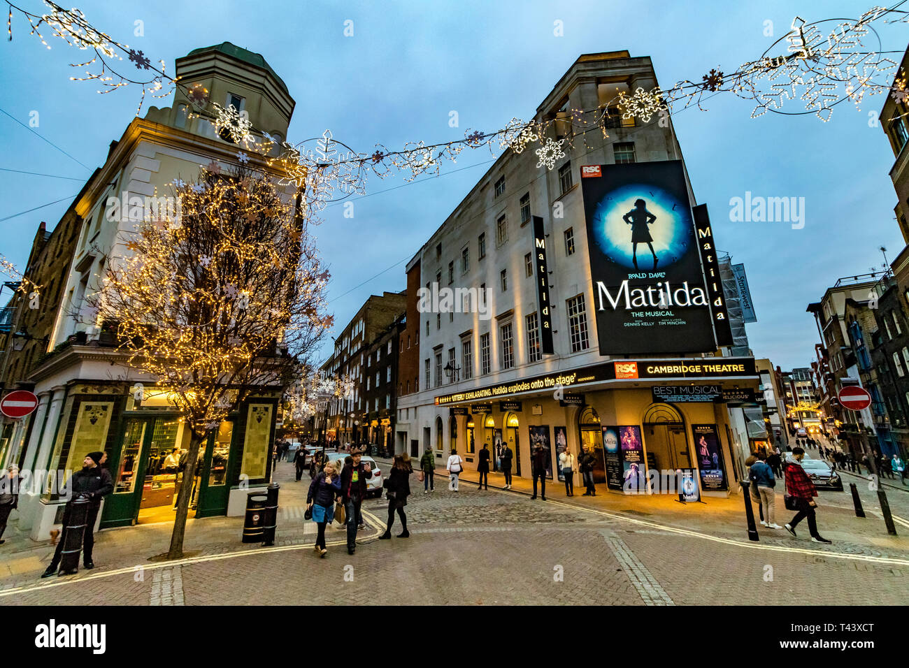 Illuminations de Noël à Seven Dials, avec des amateurs de shopping et des visiteurs passant devant le Cambridge Theatre, montrant Matilda the musical , Londres, Royaume-Uni Banque D'Images