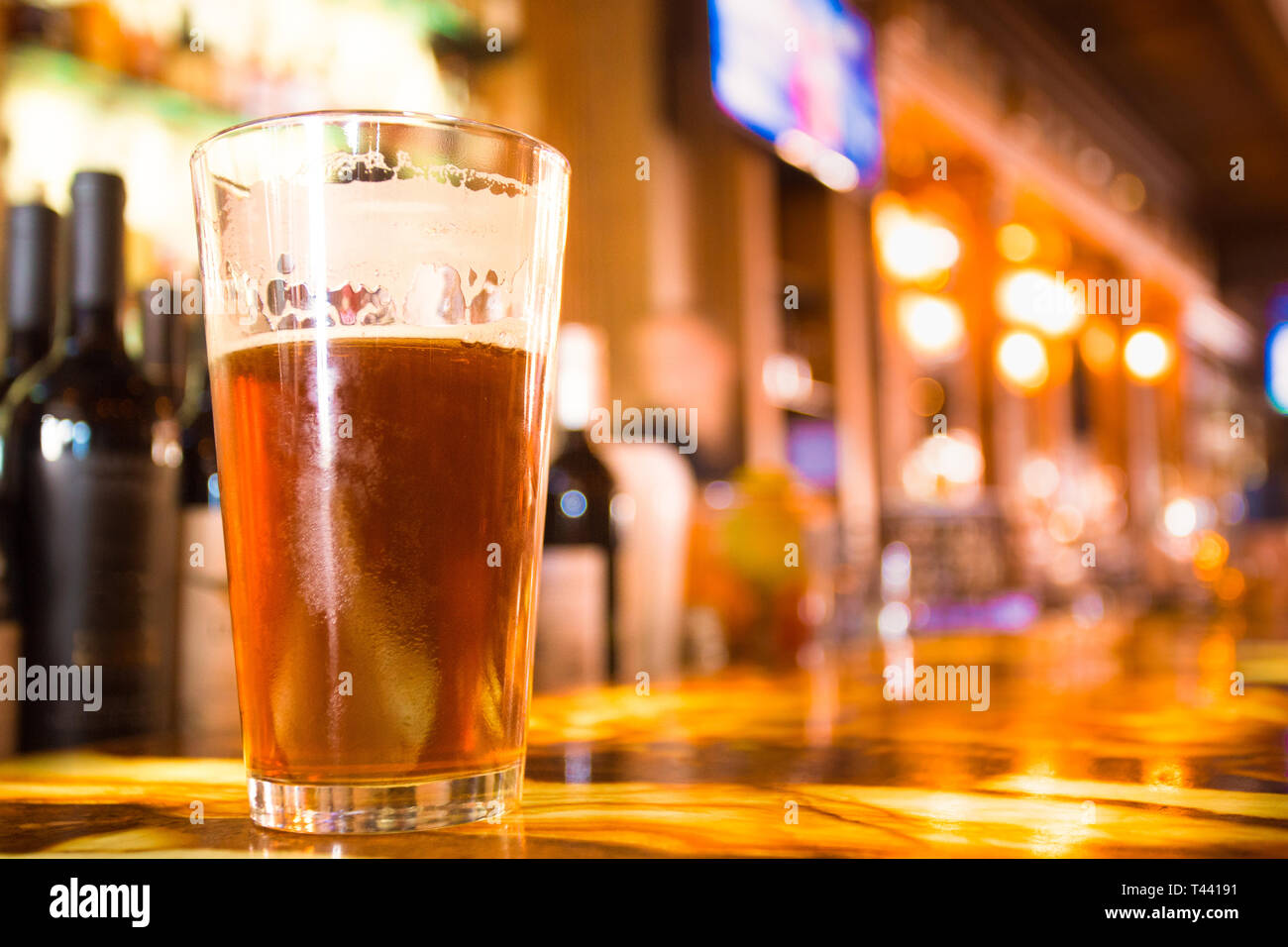 Pinte de bière en verre ambré avec flou coloré de bar en arrière-plan Banque D'Images