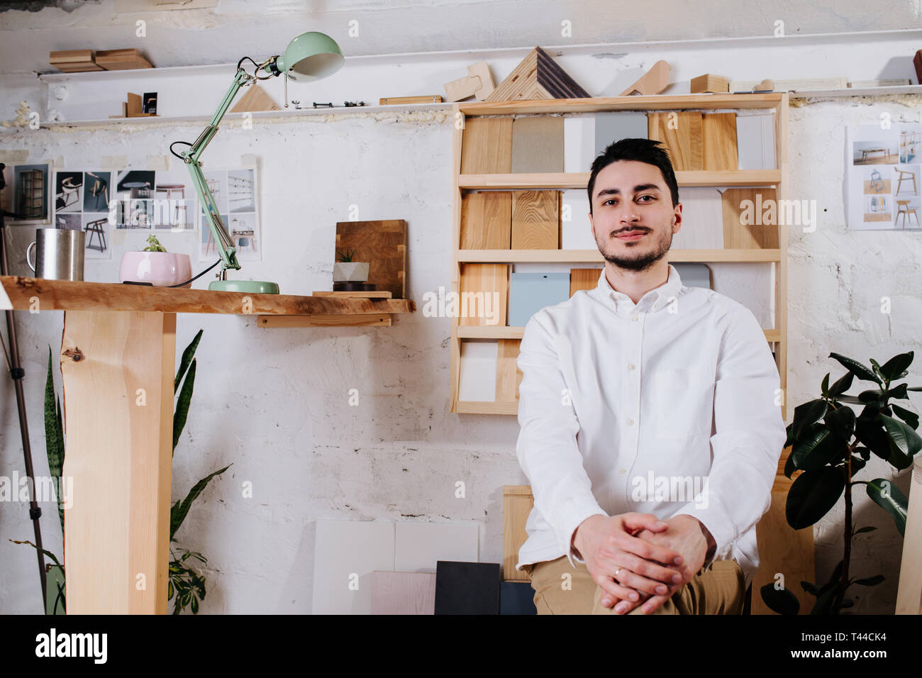 Portrait de l'environnement d'un happy smiling handsome middle aged brunet designer de meubles bouilloire dans son atelier derrière 24. haut la main Des échantillons de bois Banque D'Images