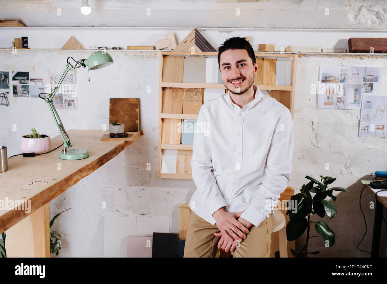 Portrait de l'environnement d'un happy smiling handsome middle aged brunet designer de meubles bouilloire dans son atelier derrière 24. haut la main Des échantillons de bois Banque D'Images