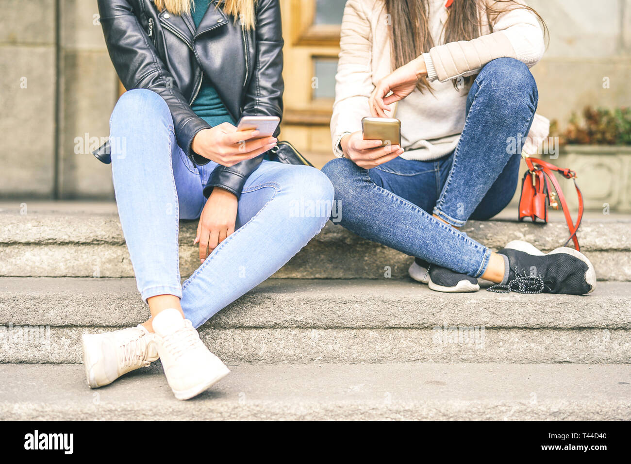 Les jeunes femmes à l'aide de téléphone mobile tout en étant assis sur des escaliers d'une zone urbaine - la jeune génération accro aux nouveaux téléphones intelligents appareils électroniques Banque D'Images