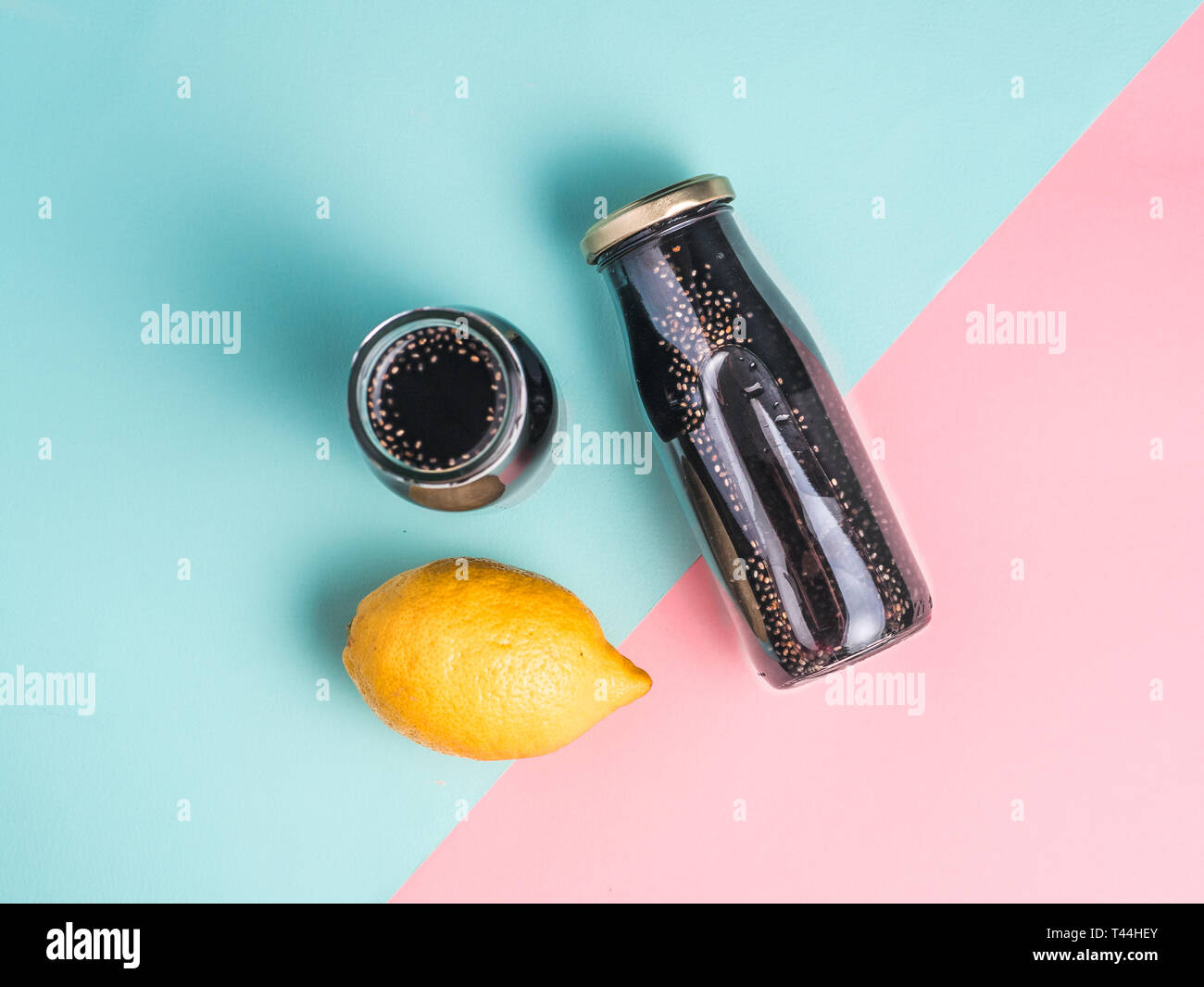 Detox noir charbon activé ou l'eau de chia au citron limonade colorés sur fond rose et bleu.Deux bouteille avec de l'eau infusée chia noir boisson Detox.idée et recette.Vegan food and drink.vue d'en haut Banque D'Images