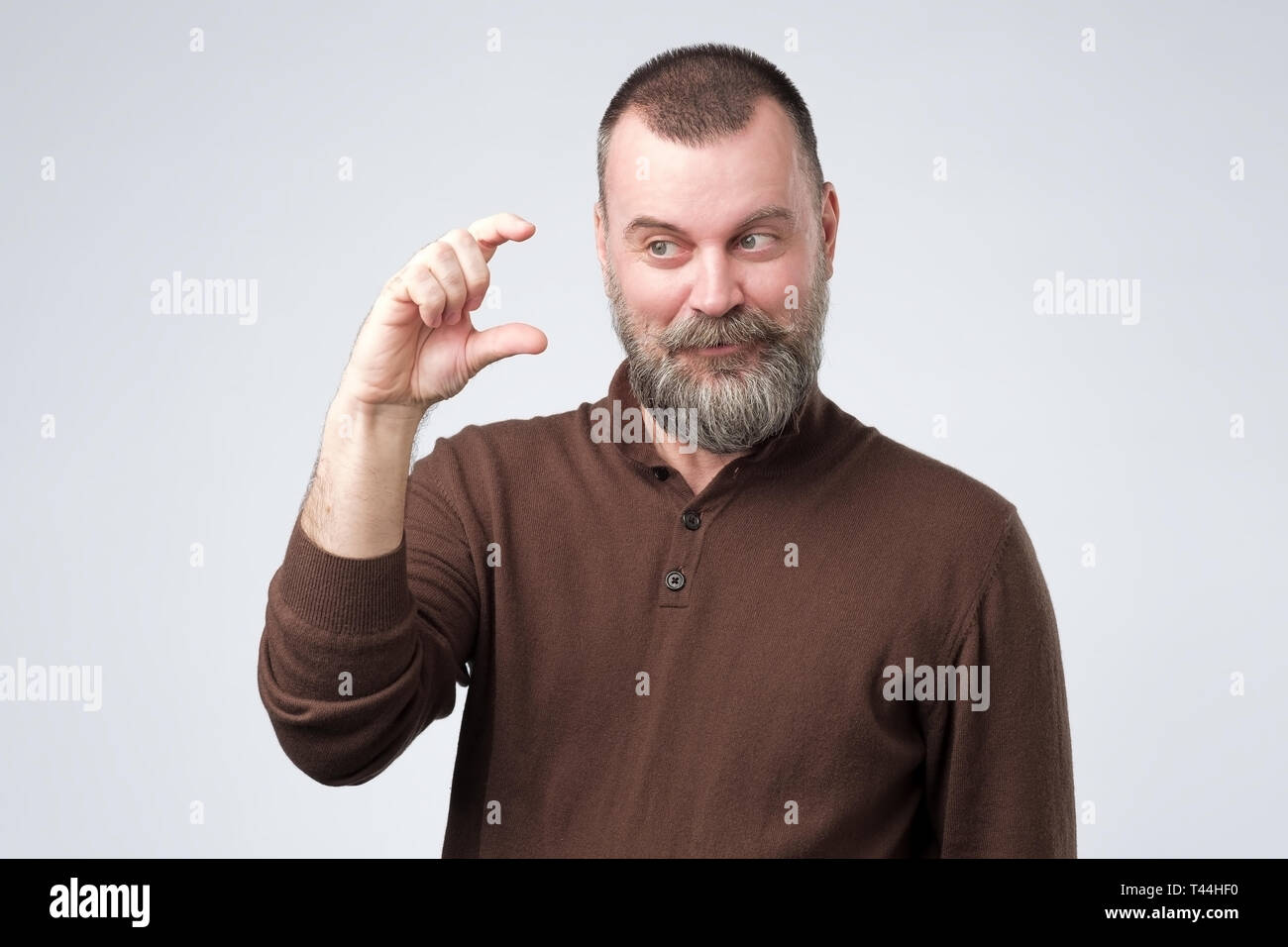 Mature man gesturing with hand montrant petite taille Banque D'Images