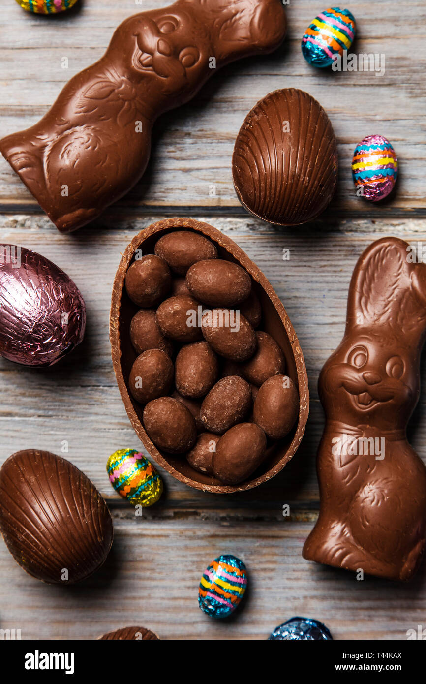 Les oeufs de pâques en chocolat et les lapins sur un fond de bois rustique Banque D'Images