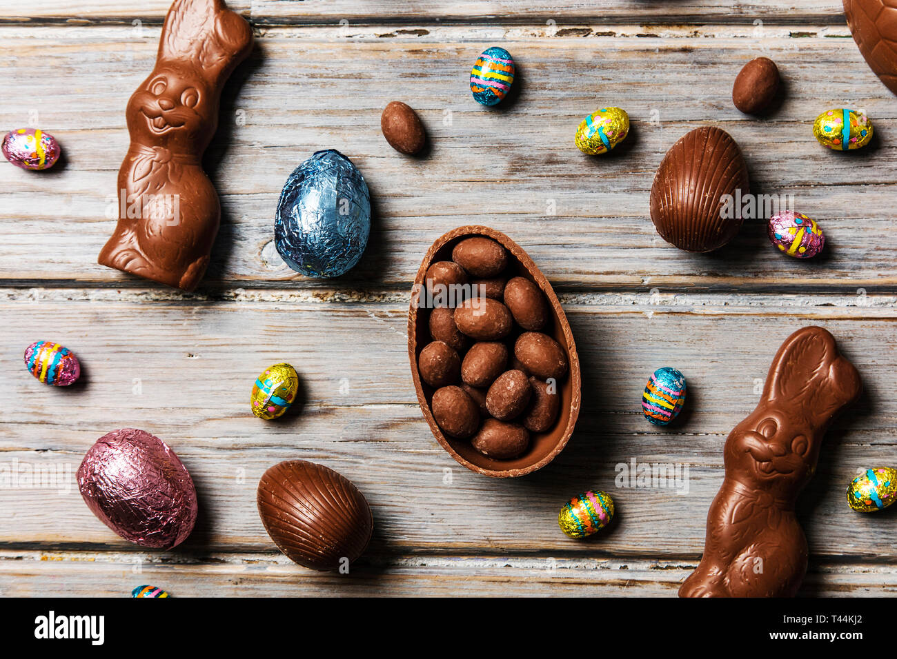 Les oeufs de pâques en chocolat et les lapins sur un fond de bois rustique Banque D'Images