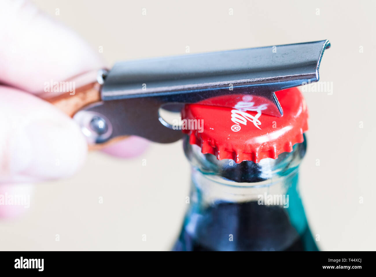 Moscou, Russie - le 4 avril 2019 : l'ouverture d'un bouchon de bouteille en verre de Coca-Cola par ouvre-bouteille close up. Coca-Cola (coke) est raccord spécifique fabriquant de boissons gazeuses Banque D'Images