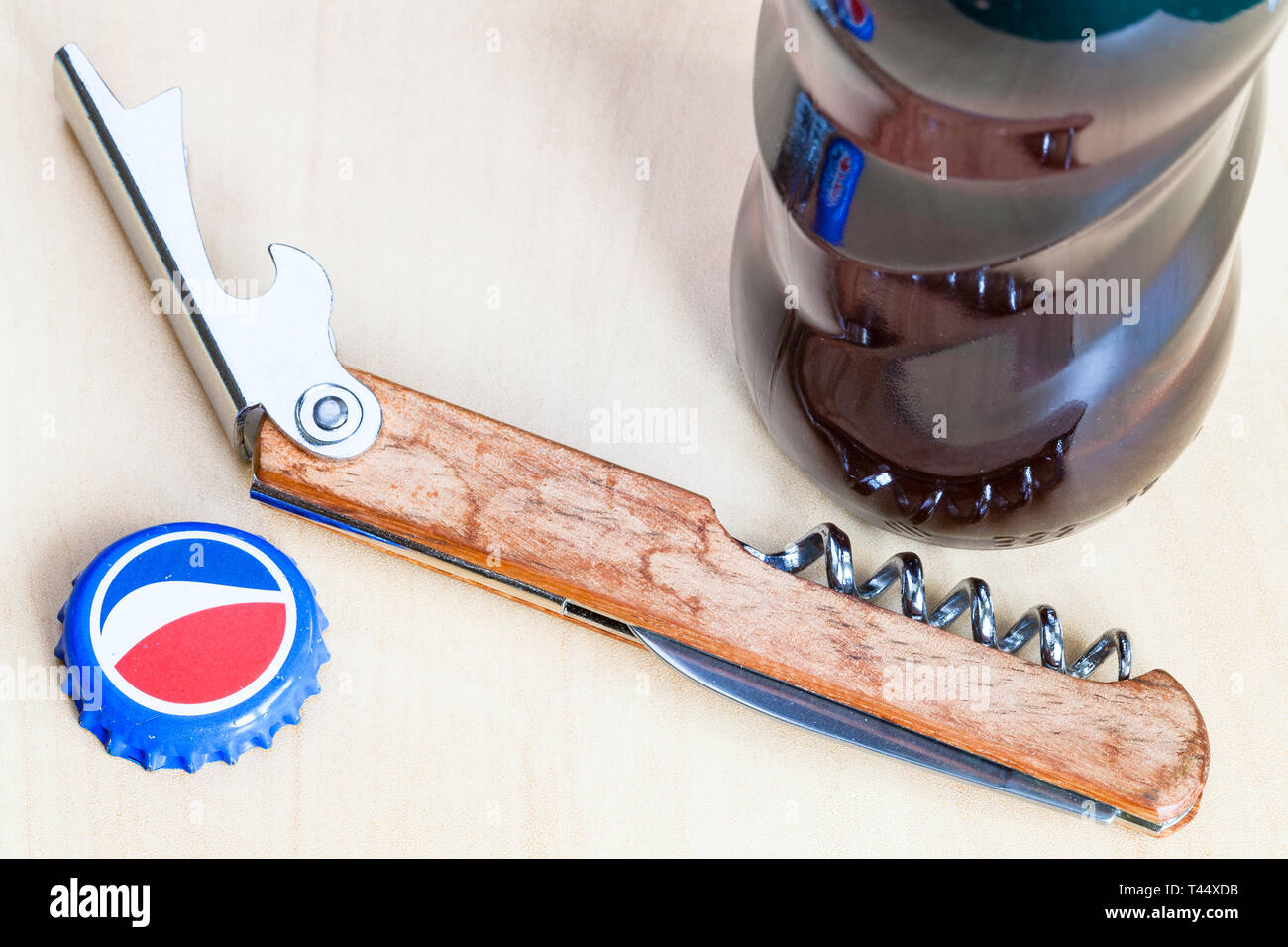 Moscou, Russie - le 4 avril 2019 : cap couronne et ouvre-bouteille près de bouteille en verre de Pepsi sur planche de bois close up. Boisson gazeuse Pepsi est manu Banque D'Images
