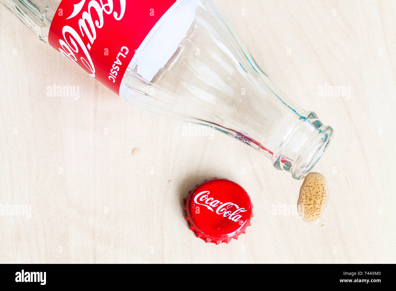 Moscou, Russie - le 4 avril 2019 : cap Couronne, bouteille vide de boisson Coca-Cola et goutte de verre sur planche de bois. Coca-Cola (coke) gazéifiée Banque D'Images