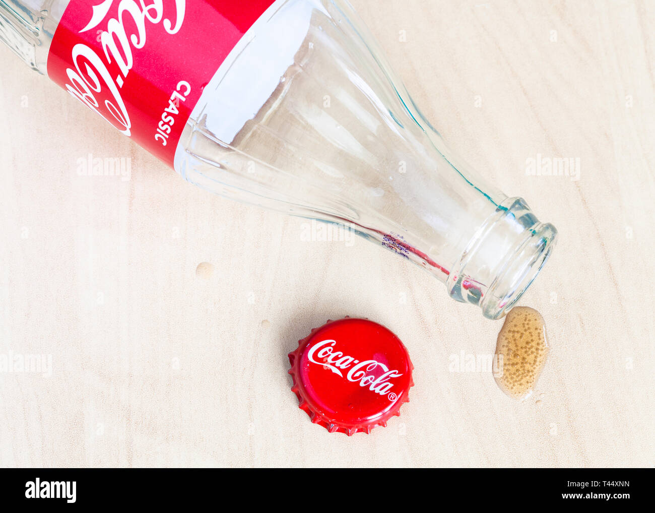 Moscou, Russie - le 4 avril 2019 : cap couronne rouge, bouteille vide de boisson Coca-Cola et goutte de verre sur table en bois. Coca-Cola (coke) gazéifiée Banque D'Images
