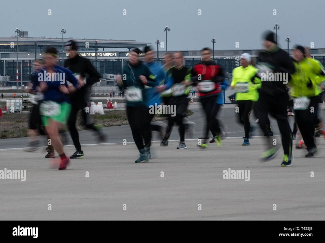 Berlin, Allemagne. 13 avr, 2019. Les participants à la course nocturne de l'aéroport '2019' courir à travers l'aéroport de BER. La 13e nuit de l'aéroport mène des milliers de coureurs dans les heures du soir le long de la borne et les quais, sous les ponts d'embarquement, sur la piste du sud ont tiré. Crédit : Paul Zinken/dpa/Alamy Live News Banque D'Images