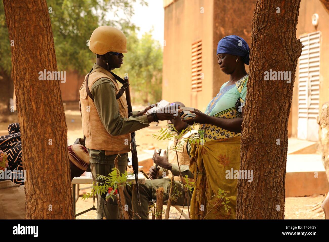 Un soldat burkinabé distribue des fournitures médicales à une femme d'un village à la périphérie de Bobob-Dioulasso, Burkina Faso 25 février 2019. Des soldats burkinabé ont distribué des fournitures médicales et de communiquer aux sections locales comment prendre le médicament prescrit par le médecin de l'armée burkinabé pendant des heures au cours de la MEDCAP événement. Banque D'Images