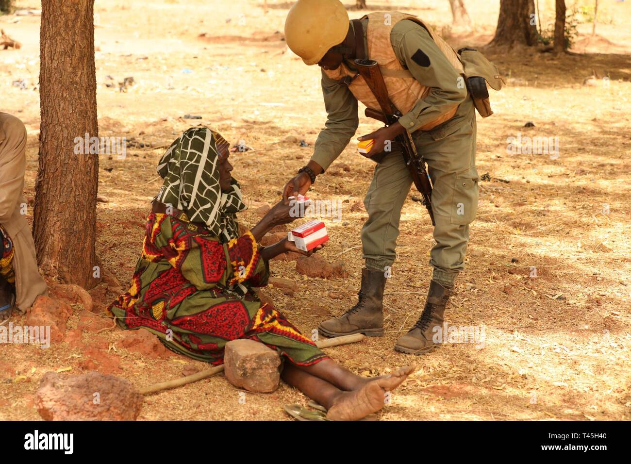 Un soldat burkinabé distribue des médicaments pour une femme âgée d'un village à la périphérie de Bobo-Dioulasso, Burkina Faso, 25 février 2019. L'action civile médicale led burkinabé Programme Programme des villageois locaux permet de voir les soldats burkinabé en tenant un droit dans le bien-être de la population locale. Banque D'Images