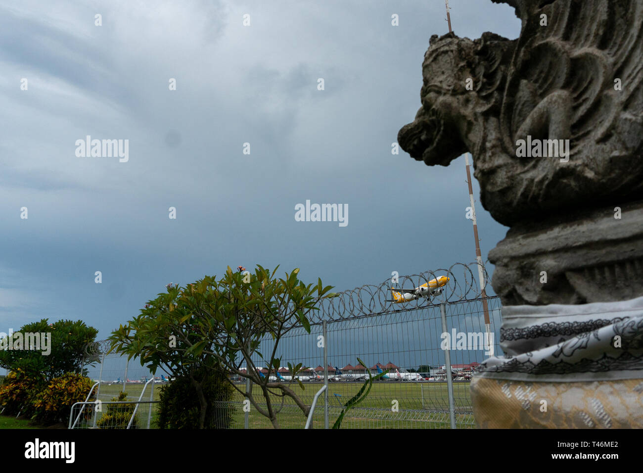 Indonésie/BALI-Avril 05 2019 : Scoot airline décoller à l'aéroport de Bali Ngurah Rai quand ciel est nuageux gris avec la statue de Bali en avant-plan Banque D'Images