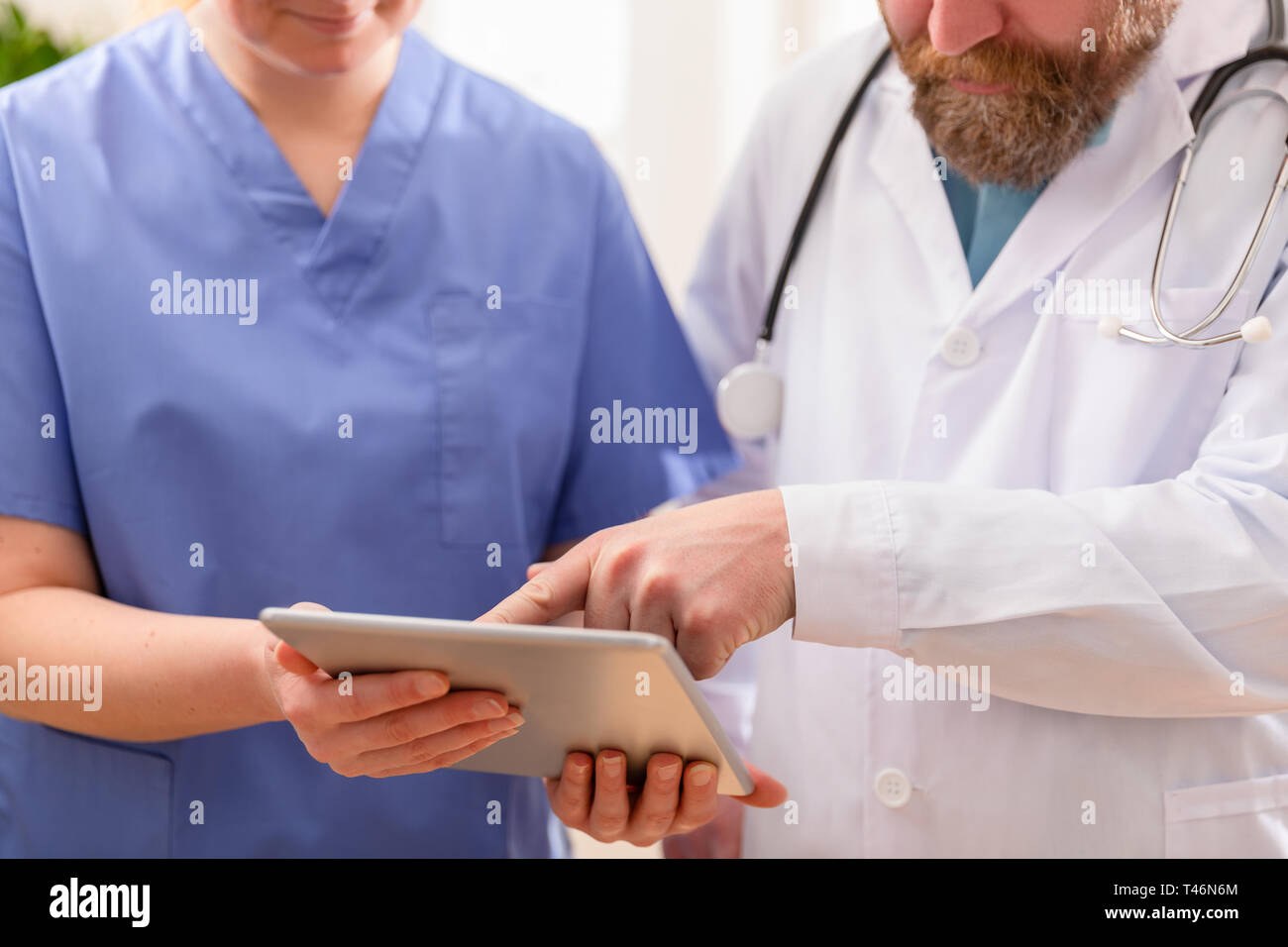 Doctor and nurse discussing patients essais a tablet computer in hospital Banque D'Images