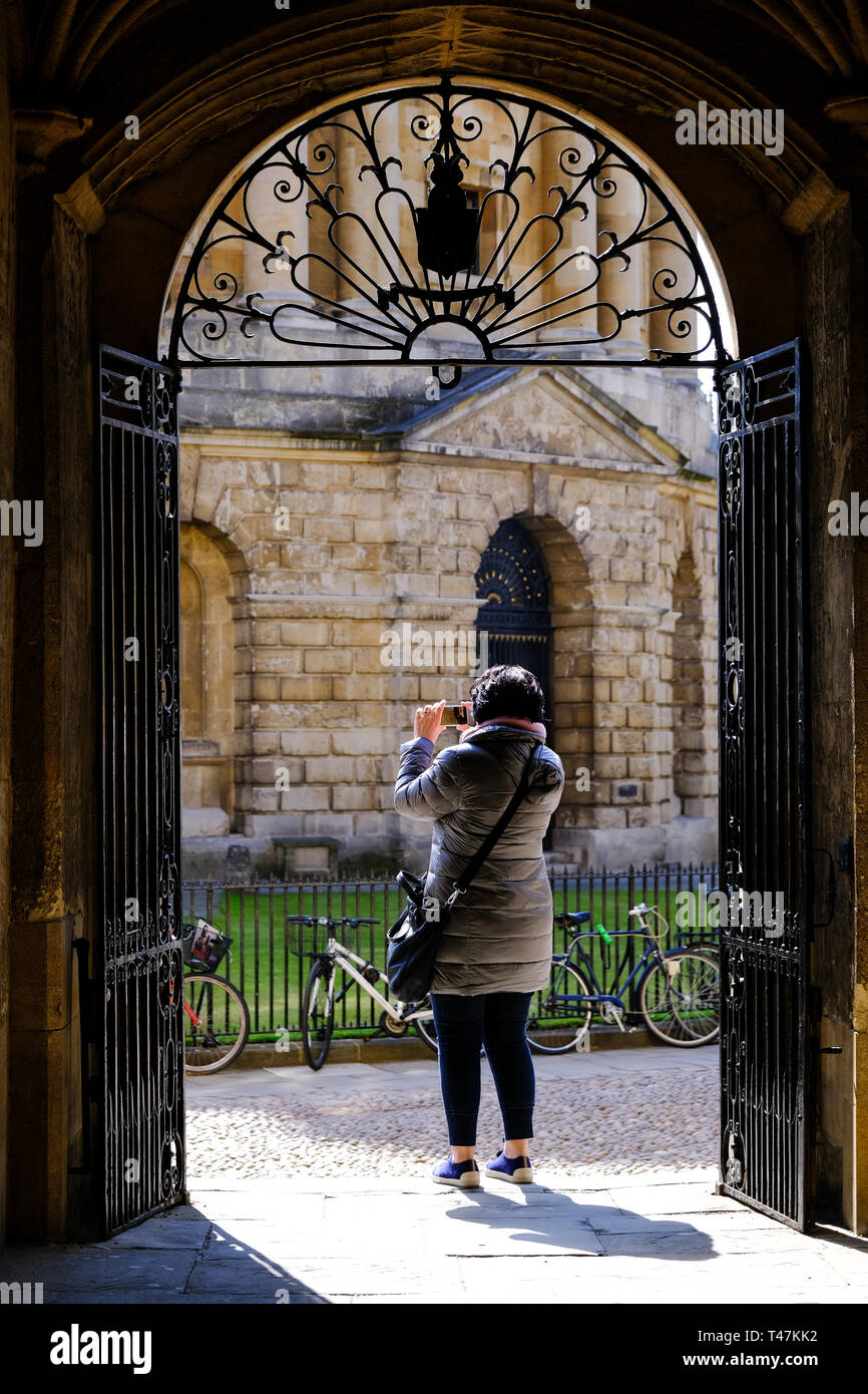 Un visiteur de la Bodleian Library, qui fait partie de l'Université d'Oxford qui est une attraction touristique populaire de s'arrêter pour prendre une photo de Radcliffe Camera lire Banque D'Images