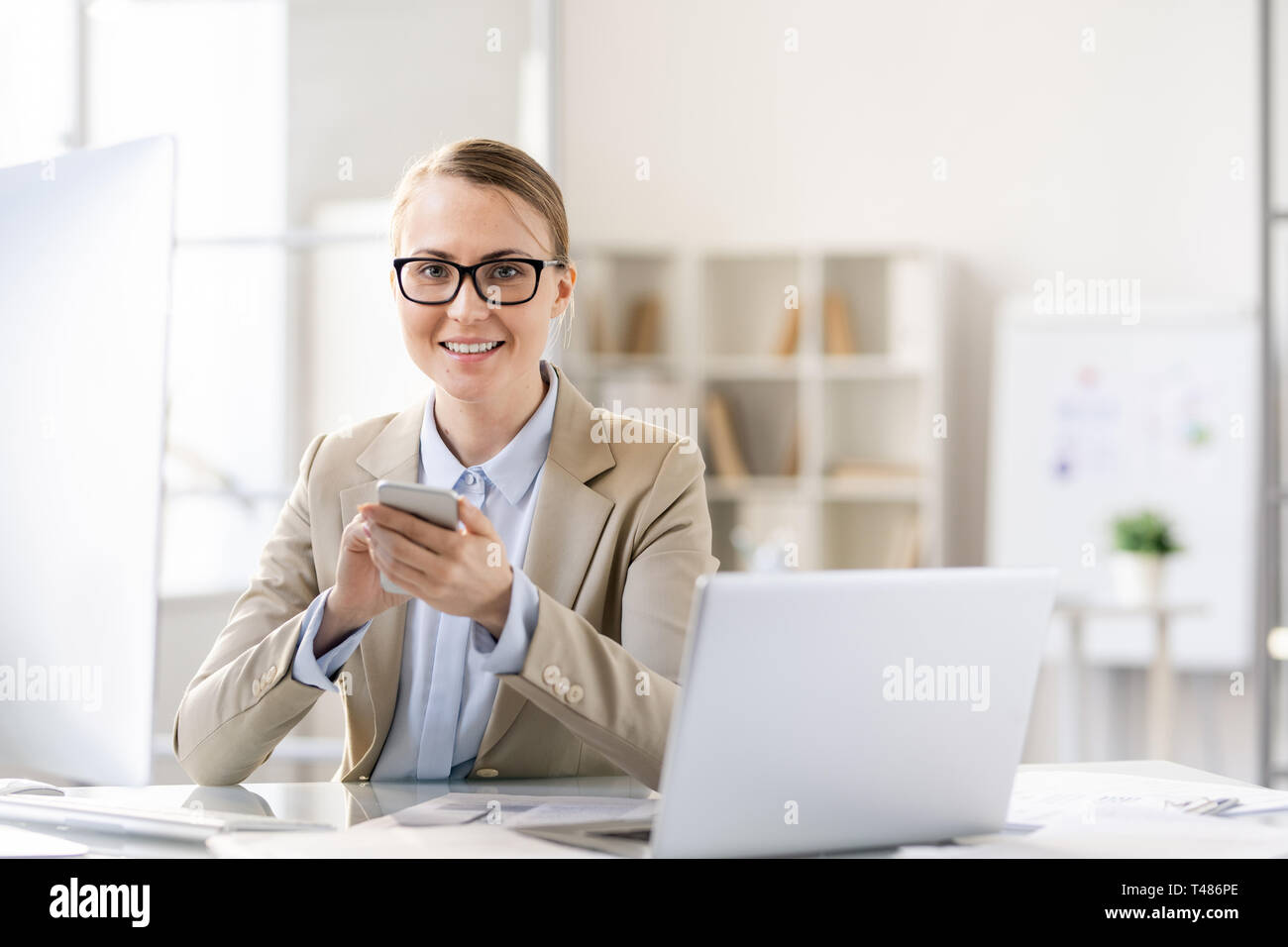 Happy pretty lady texting message tandis que working in office Banque D'Images