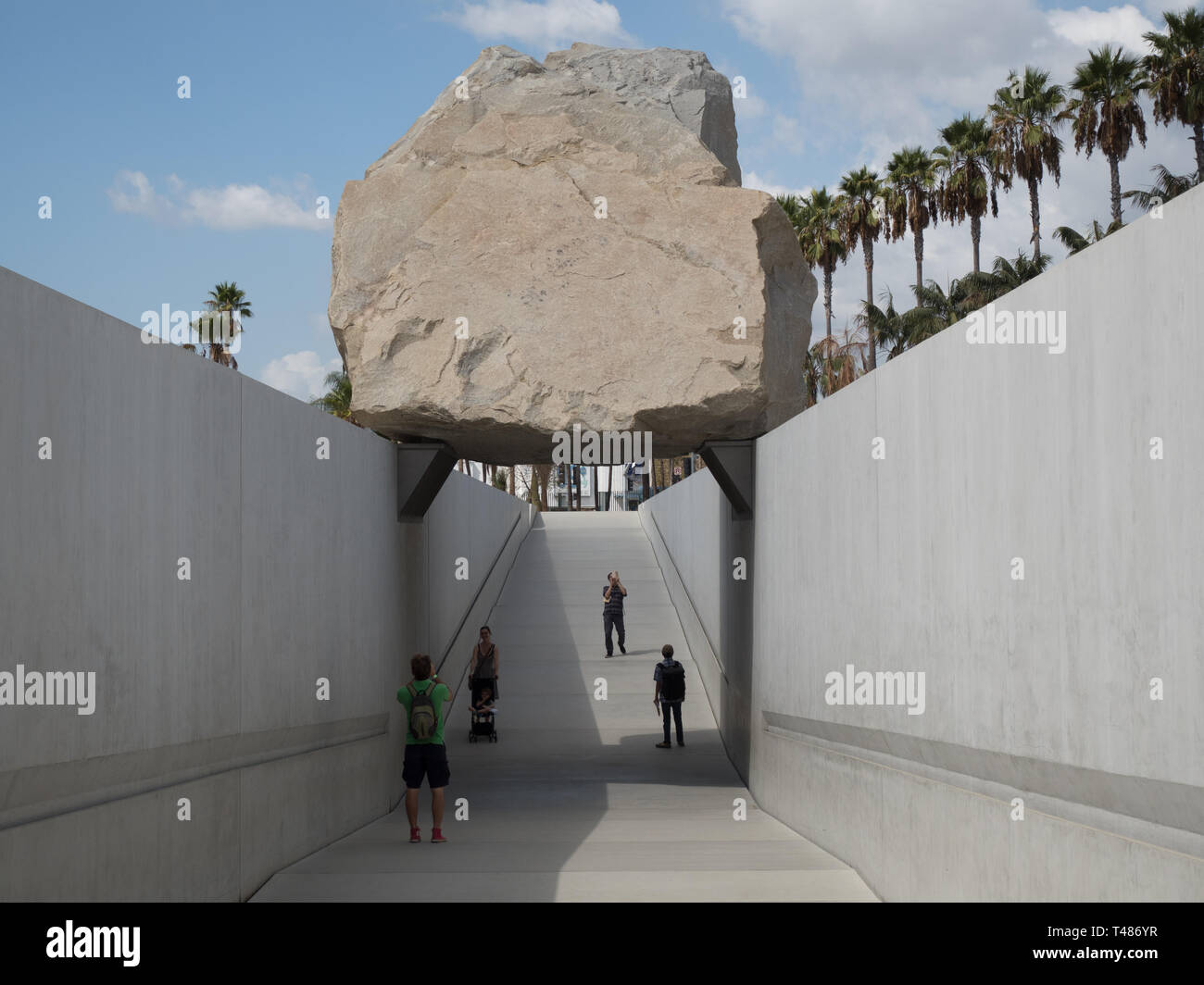 Les gens marchent sous la sculpture de masse en Lévitation par Michael Heizer au Los Angeles County Museum of Art Banque D'Images