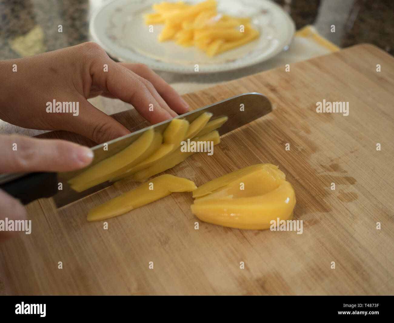Trancher des fruits en conserve sur une planche à découper en bois Banque D'Images