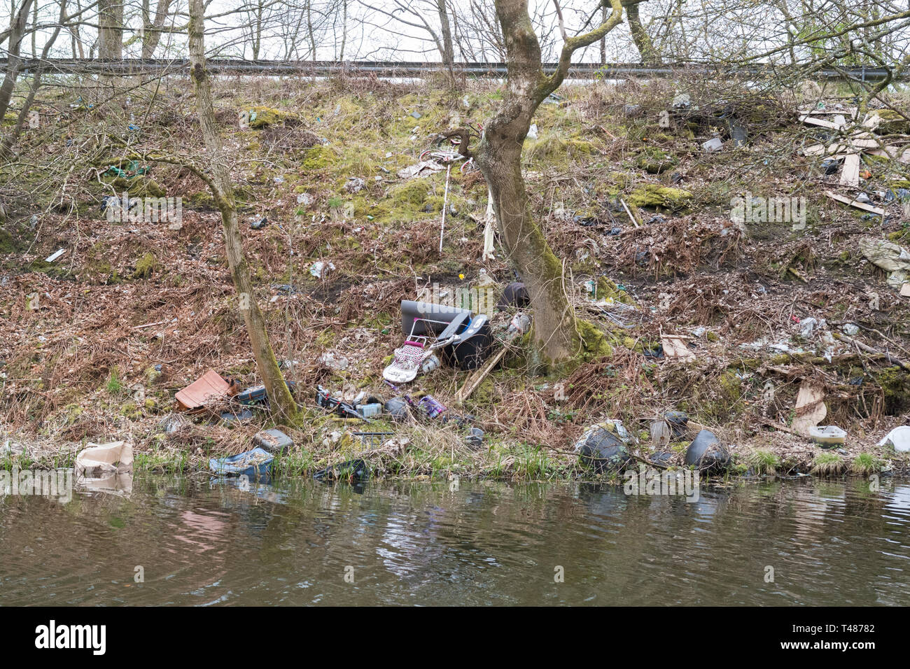 Les décharges sauvages Ecosse - déchets jetés depuis la route sur la rive de la Forth and Clyde Canal près de Kirkintilloch, Ecosse, Royaume-Uni Banque D'Images