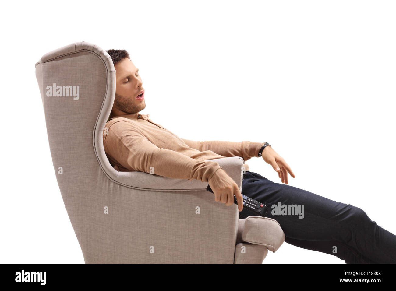 Jeune mec avec une télécommande de dormir dans un fauteuil isolé sur fond blanc Banque D'Images