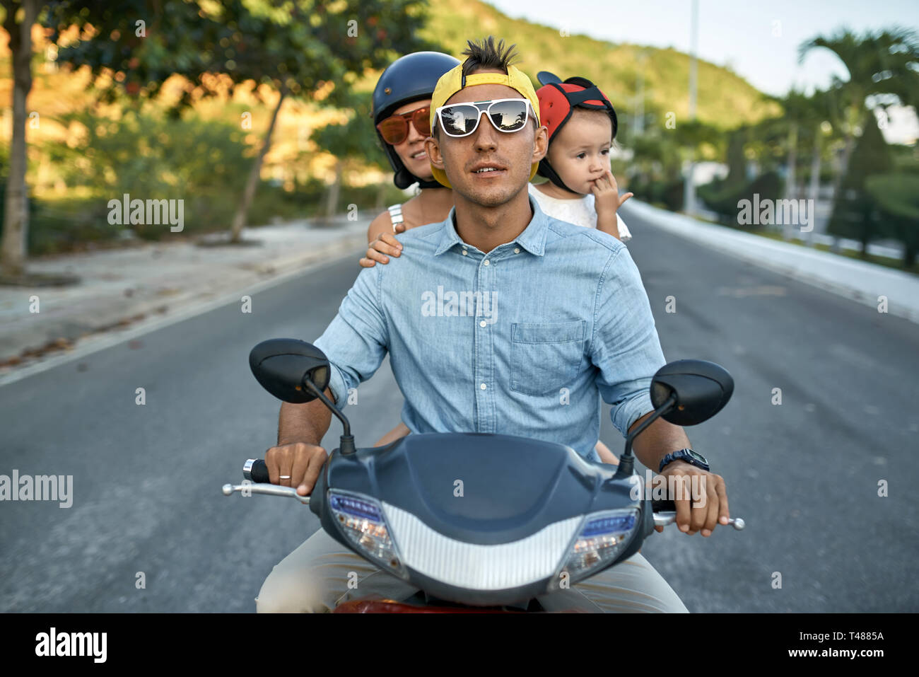 Les parents avec leur petit enfant riding sur sunny city street Banque D'Images