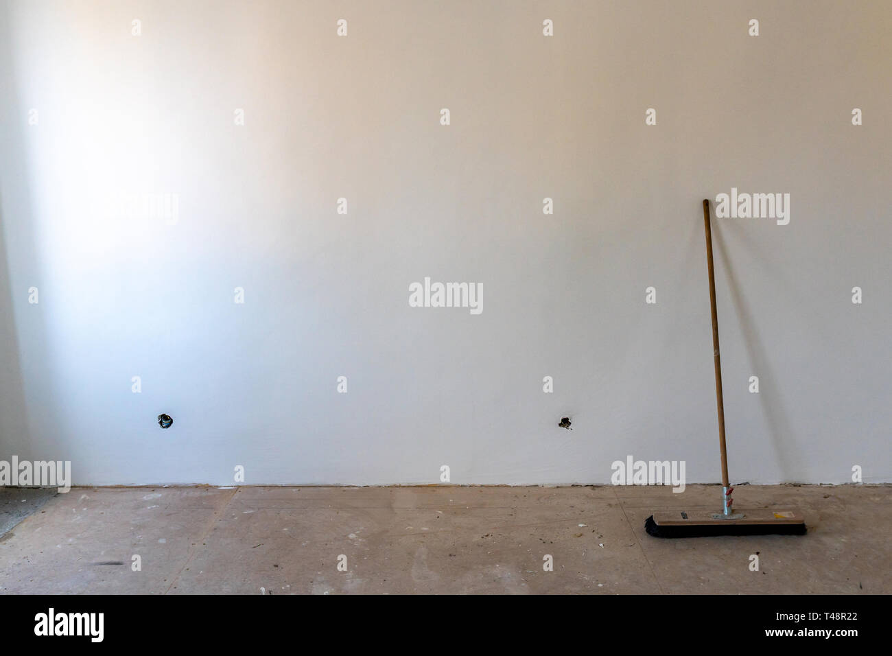 Crin noir commun balayant Broom s'appuyant sur un mur peint de couleur blanche dans un appartement avec connecteurs vides d'énergie électrique Banque D'Images